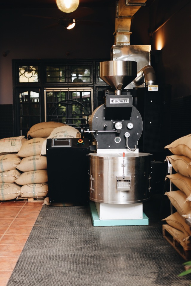 Khu vực rang cà phê với những bao tải cà phê nhân và máy rang chuyên nghiệp.